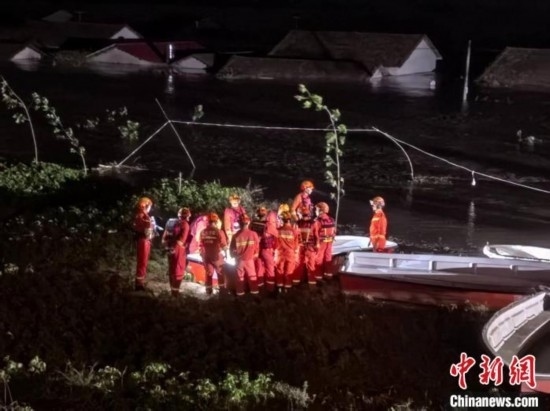  7月6日凌晨3時，在湖南岳陽華容縣團洲垸洞庭湖一線堤防，救援人員剛剛完成一次救援任務，遠處是被淹的民房。中新社記者 白祖偕 攝