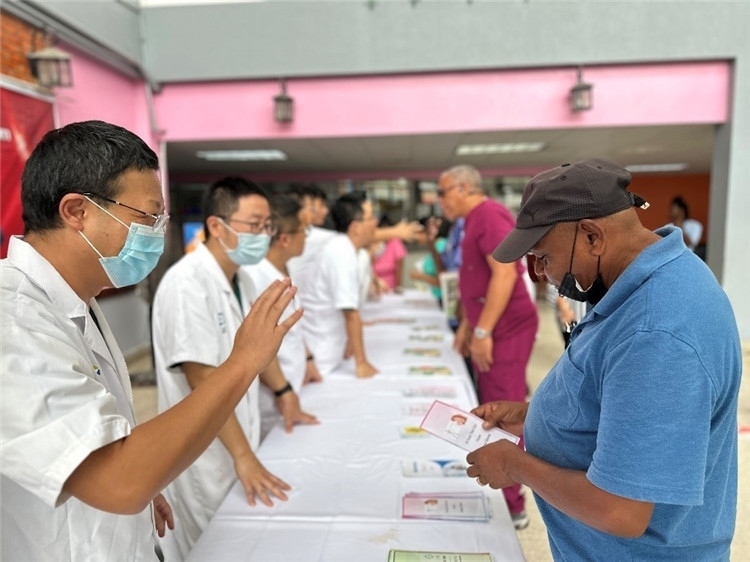 援圭醫(yī)療隊(duì)隊(duì)員們?cè)趩?dòng)儀式上為當(dāng)?shù)孛癖姺职l(fā)宣傳手冊(cè)。中國(guó)援助圭亞那醫(yī)療隊(duì)供圖