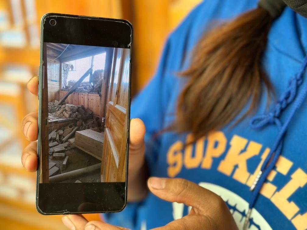 圖為7月17日拉毛東智在手機上找出地震后房屋受損的照片。新華社記者 張子琪 攝