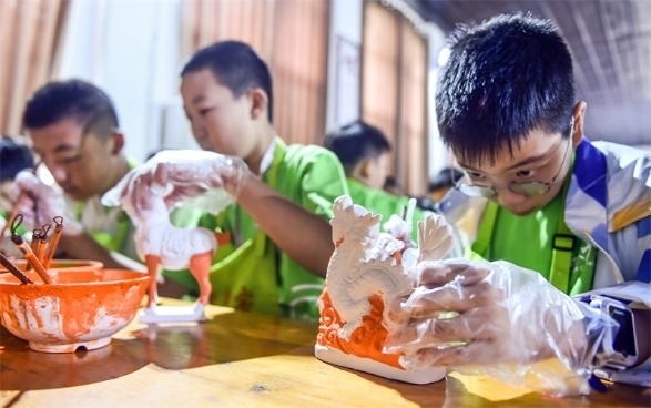 小朋友們?cè)诼尻?yáng)市孟津區(qū)朝陽(yáng)鎮(zhèn)南石山村體驗(yàn)唐三彩素胎施釉技藝。圖片來(lái)源：視覺(jué)中國(guó)