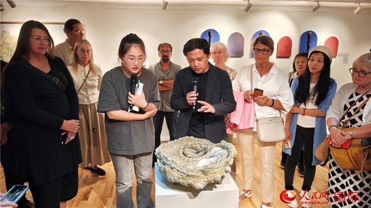 參展人、景德鎮(zhèn)陶瓷大學(xué)設(shè)計(jì)藝術(shù)學(xué)院副院長(zhǎng)余劍峰（中）向來(lái)賓介紹參展作品。人民網(wǎng)記者 殷淼攝