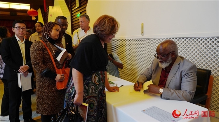 譚哲理在活動現(xiàn)場簽名贈書。人民網(wǎng) 劉暢攝