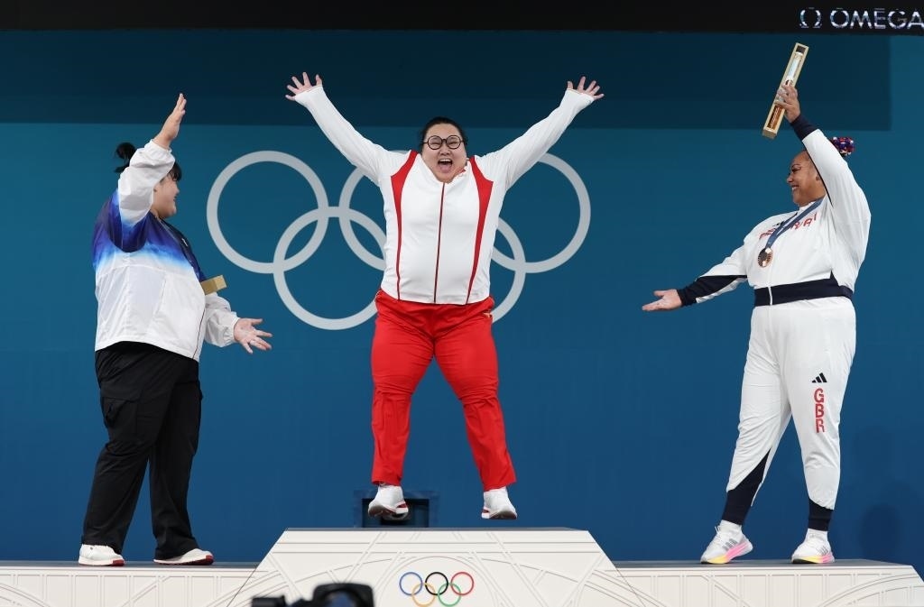 中國選手李雯雯（中）在巴黎奧運(yùn)會(huì)舉重女子81公斤以上級(jí)頒獎(jiǎng)儀式中登上領(lǐng)獎(jiǎng)臺(tái)（2024年8月11日攝）。新華社記者 楊磊 攝