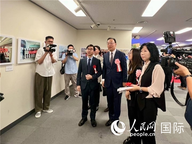 中國國際航空日韓地區(qū)支社支社長馮力為中國駐日本大使館臨時(shí)代辦施泳等嘉賓介紹展出圖片。人民網(wǎng) 許可攝