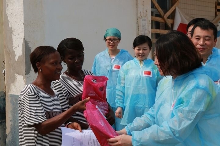 2015年4月4日，在位于塞拉利昂首都弗里敦市郊的中塞友好醫(yī)院埃博拉診療中心，中國(guó)第四批援塞醫(yī)療隊(duì)副隊(duì)長(zhǎng)邵蔚（右前）向被治愈的埃博拉出血熱患者贈(zèng)送禮物。新華社發(fā)（祖榮強(qiáng) 攝）
