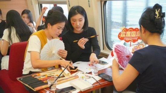 10月1日，旅客們在G1634次列車上給油紙傘作畫。新華社記者周義 攝