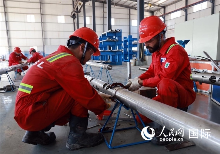 中伊員工共同在檢修鉆井設(shè)備。人民網(wǎng)記者管克江攝