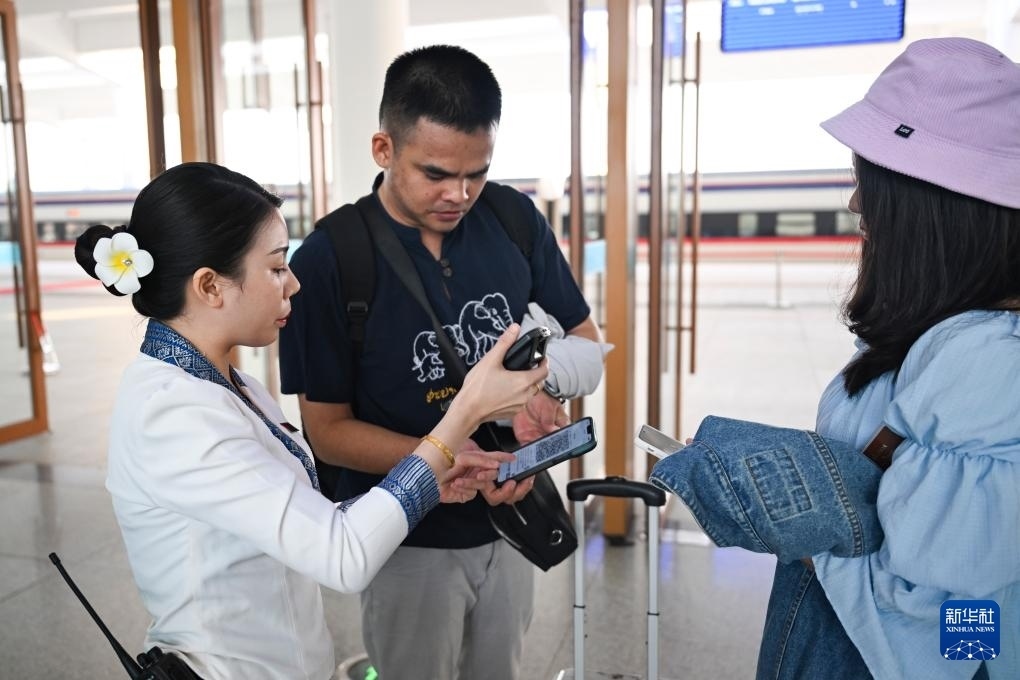 10月12日，在老撾萬象中老鐵路萬象站，工作人員檢驗(yàn)乘客車票。新華社記者 程一恒 攝