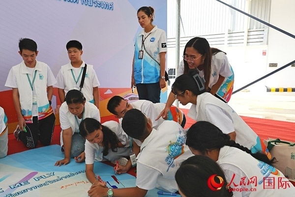 泰國學生在開營儀式展板上繪制圖案。人民網(wǎng)記者 白元琪攝