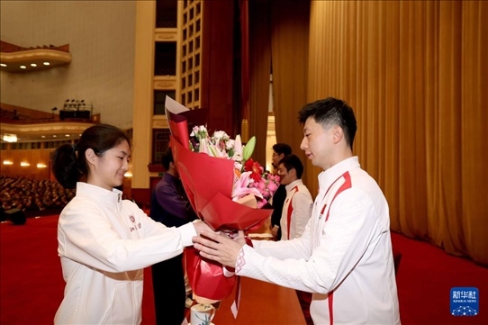 11月15日，一名學(xué)生代表在報告會上向乒乓球運動員馬龍（右）獻花。新華社記者 李明 攝