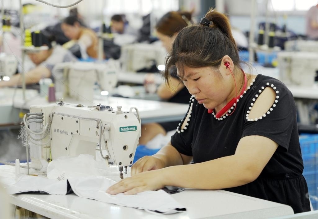 5月20日，村民在李寨村服裝加工廠內(nèi)忙碌。河南省周口市沈丘縣馮營鎮(zhèn)李寨村地處豫東平原。近年來，乘著脫貧攻堅與鄉(xiāng)村振興政策的東風(fēng)，李寨村積極探索產(chǎn)業(yè)發(fā)展模式，通過“龍頭企業(yè)+村集體經(jīng)濟+農(nóng)戶”的方式，逐漸發(fā)展形成肉牛養(yǎng)殖、設(shè)施農(nóng)業(yè)、服裝加工、康養(yǎng)民宿等產(chǎn)業(yè)，以產(chǎn)業(yè)振興助力鄉(xiāng)村振興。新華社記者 李嘉南 攝