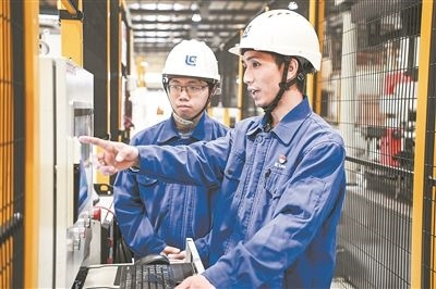 在廣西柳工機(jī)械股份有限公司生產(chǎn)車間內(nèi)，一名高級(jí)技師（右）給徒弟講解數(shù)控設(shè)備操作細(xì)節(jié)。新華社記者 曹祎銘攝