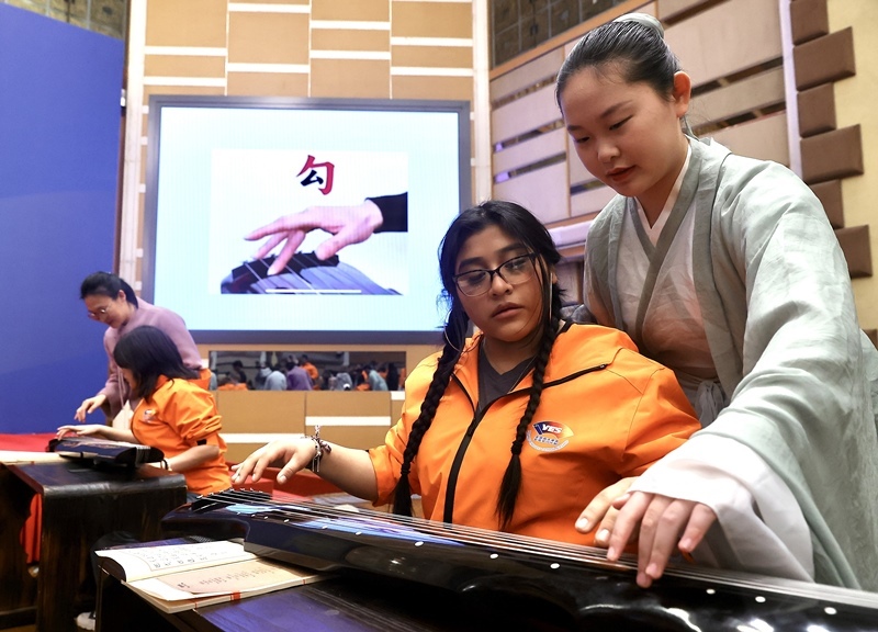 2024年3月20日，美國(guó)華盛頓州中學(xué)生代表團(tuán)北京大學(xué)交流活動(dòng)在北京大學(xué)英杰交流中心舉行。圖為來自華盛頓州的中學(xué)生體驗(yàn)古琴。