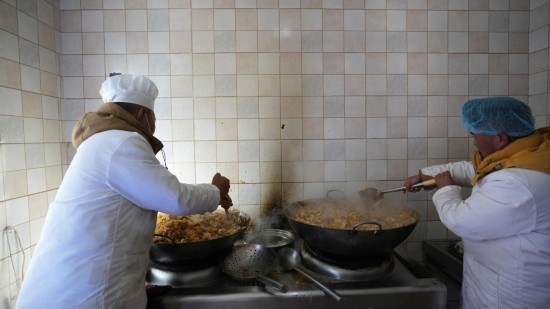 1月14日，服務(wù)隊(duì)的兩名廚師正在為村民們做午飯。新華社記者 邱星翔 攝