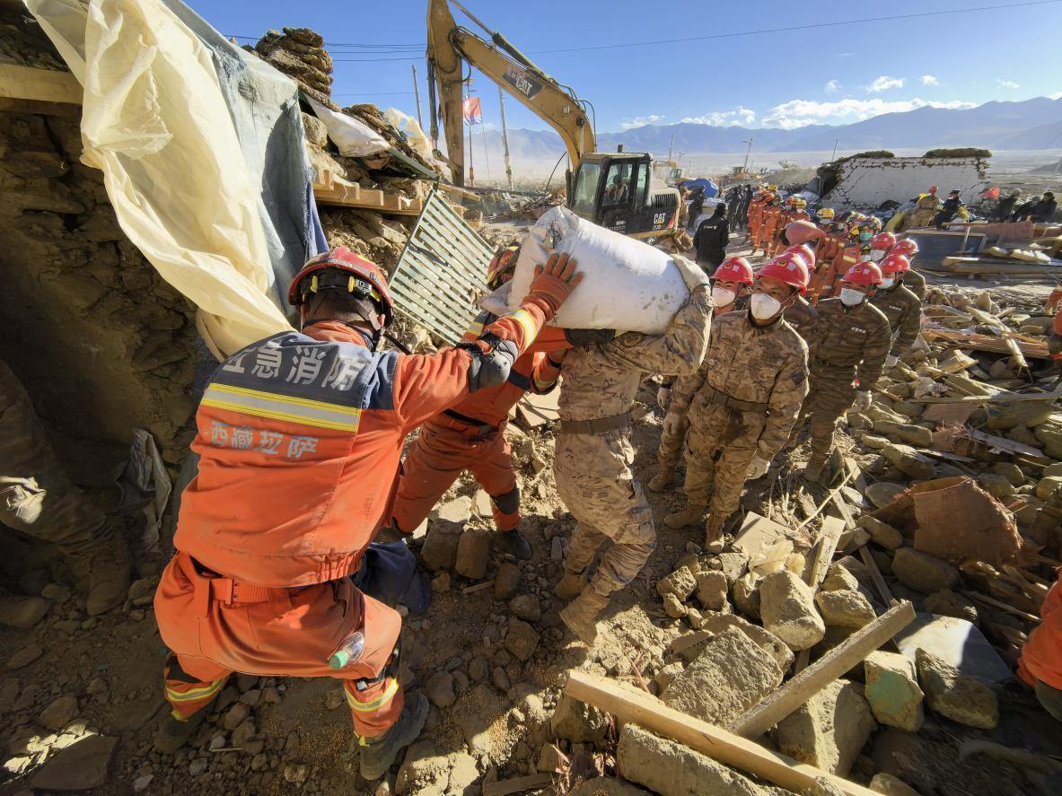 1月11日，定日縣長所鄉(xiāng)古榮村，應急消防等救援人員排隊接力搶運掩埋在倒塌房屋下的群眾財物。人民日報記者楊翹楚攝