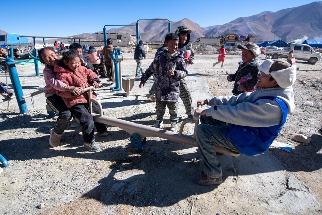1月11日，在定日縣措果鄉(xiāng)塘仁村安置點，西藏星光社會工作服務中心志愿者和孩子們一起玩耍，進行災后心理疏導。人民網記者 翁奇羽攝