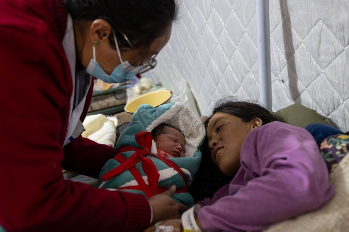 1月10日，定日縣中心醫(yī)院的婦產科醫(yī)生悉心照看一位母親和她懷里的新生兒。人民日報記者張武軍攝