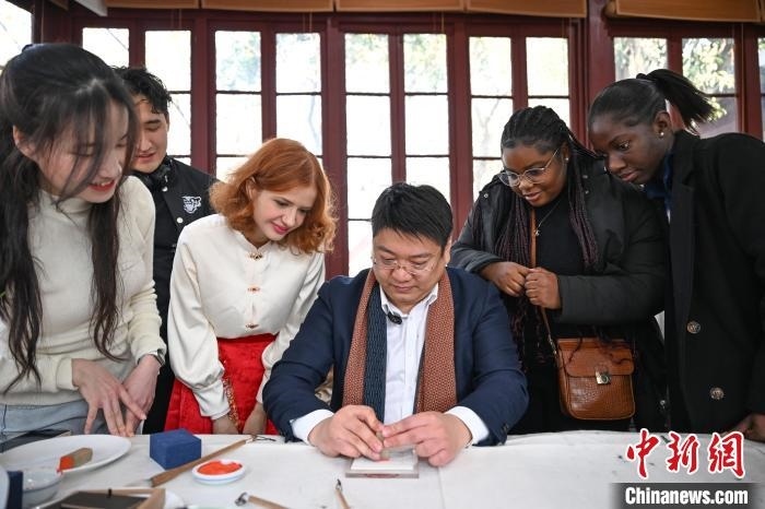 1月20日，篆刻家王臻向外籍留學(xué)生展示篆刻印章。當(dāng)日，來(lái)自巴西、馬來(lái)西亞、加納、哈薩克斯坦的外籍留學(xué)生在浙江杭州西泠印社體驗(yàn)福貼、春聯(lián)和篆刻，感受古老的中國(guó)傳統(tǒng)文化。中新社記者 王剛 攝
