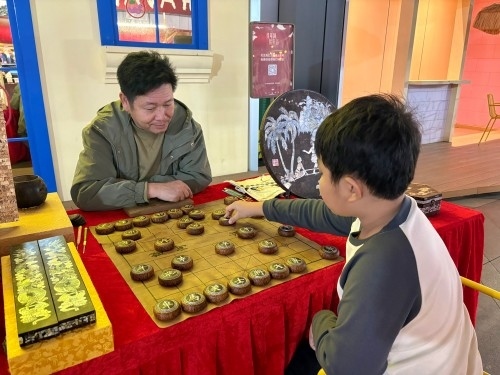 柯秋楓與市民下椰雕象棋。人民網(wǎng) 陳葉欣攝