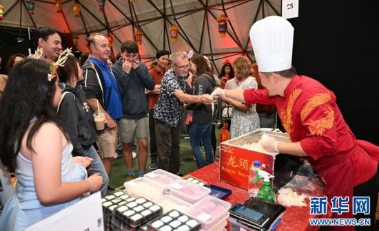 圖為游客在燈節(jié)現(xiàn)場購買小吃。（圖片由奧克蘭中國文化中心提供）