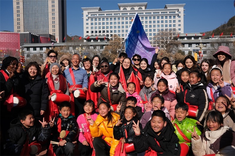 中外青年學(xué)子在安塞文化廣場(chǎng)觀看陜北腰鼓和大秧歌表演后合影留念，大家踏著鼓點(diǎn)共舞，翻飛的紅綢與躍動(dòng)的身影交織，在黃土地廣場(chǎng)上繪出一幅生動(dòng)的陜北民俗互動(dòng)畫卷