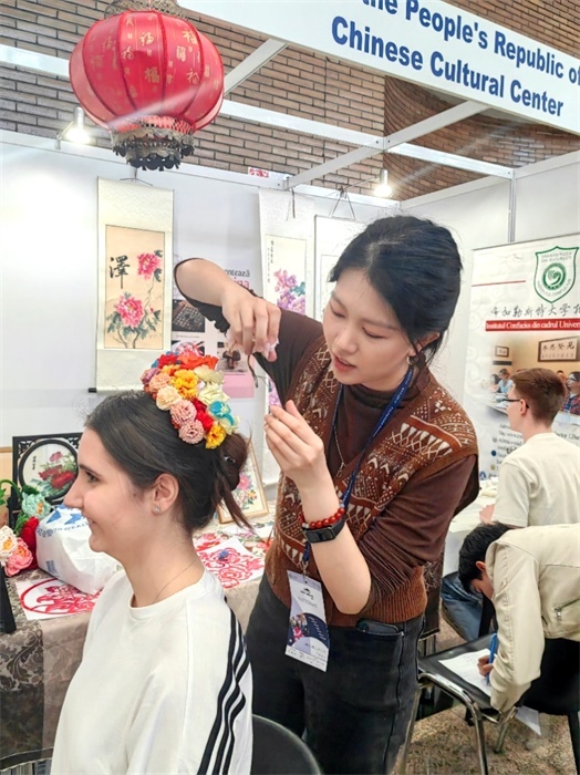 展覽正值羅馬尼亞迎春花節(jié)，國際中文教師志愿者潘婧穎向游客們介紹了國家非物質(zhì)文化遺產(chǎn)——福建泉州的簪花文化。布加勒斯特大學(xué)孔子學(xué)院供圖。