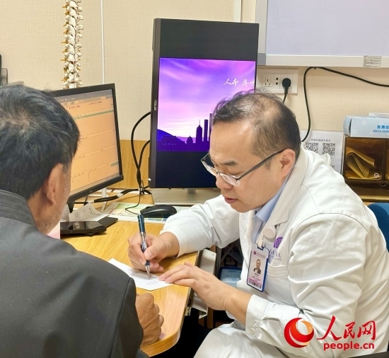 路桂軍接診時(shí)為患者寫下用藥提示。人民網(wǎng)記者 金慧慧攝