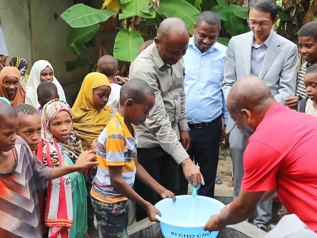 在日前舉行的安全供水工程揭牌儀式上，當?shù)匦∨笥言诠┧c接水。 施亮攝
