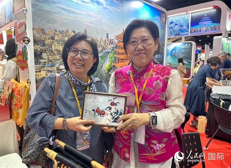 中國“大冶刺繡”傳承人劉小紅（右）參加泰國國際旅游展，向觀眾介紹中國非遺刺繡針法。人民網(wǎng)記者 簡承淵攝