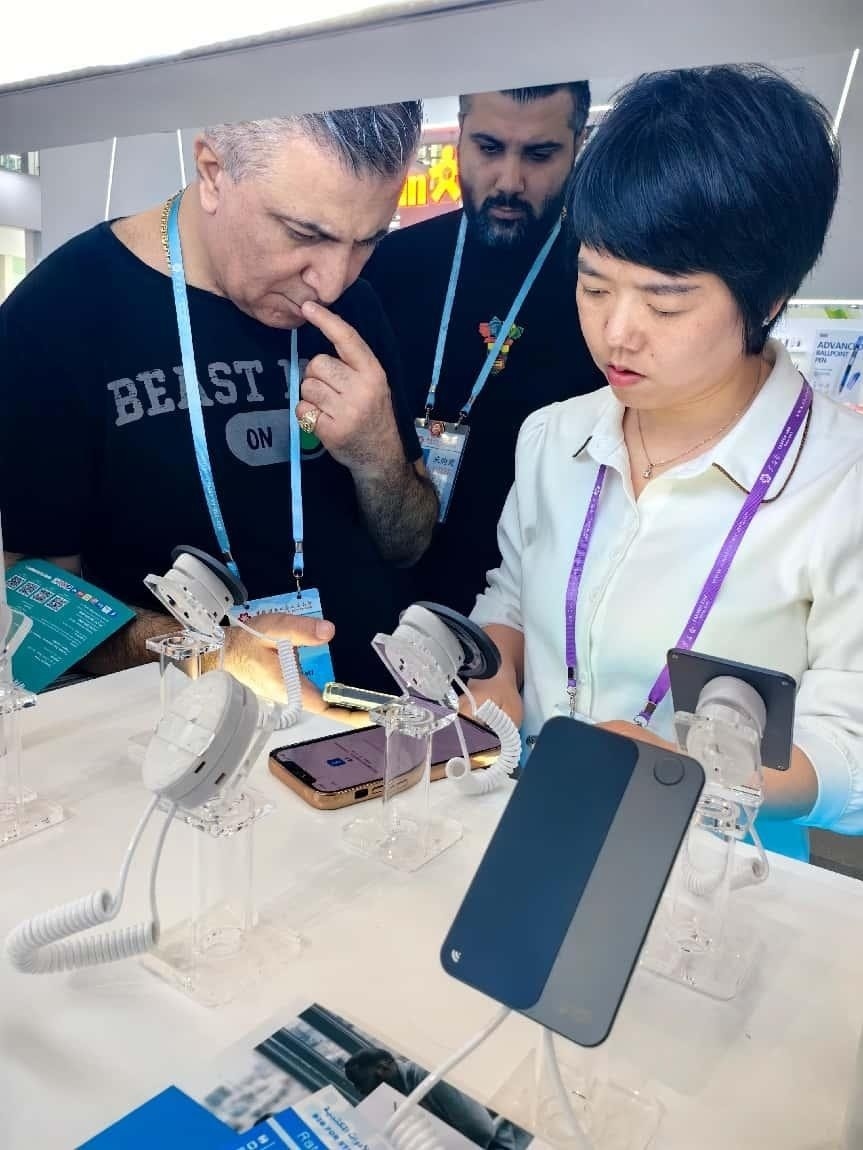 展臺工作人員向外商展示“AI TOP翻譯終端”。圖片來源：受訪者提供