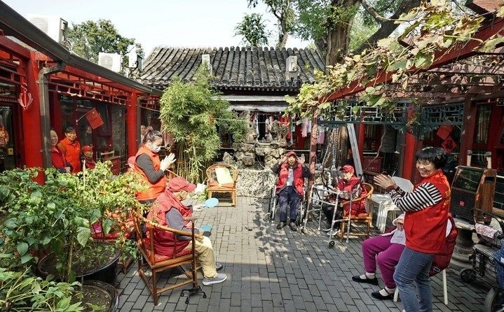 2024年10月12日，鐘樓灣胡同的老年人在社區(qū)內(nèi)的四合院養(yǎng)老驛站休閑。2017年起，北京市先后開展了兩輪背街小巷環(huán)境整治提升行動，完整保留了中軸線生活建筑群的歷史信息，并根據(jù)居民的生活和居住方式進(jìn)行適配化的更新和改造，極大地改善了生活環(huán)境。2023年鐘樓灣胡同被評為“北京最美街巷”。