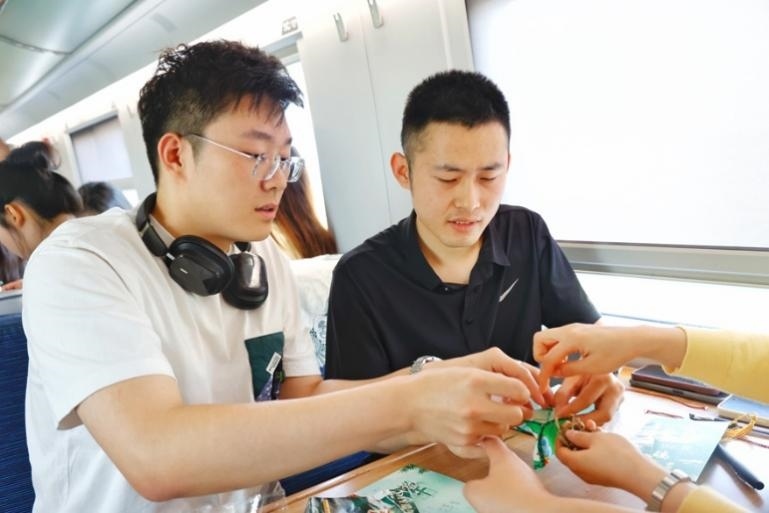 G232次旅客親手制作端午荷包和五彩繩。王磊攝