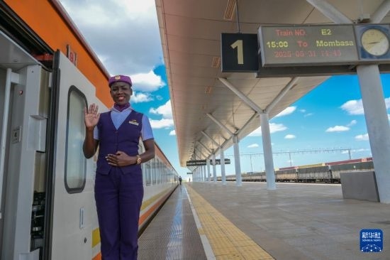 5月31日，在蒙內(nèi)鐵路內(nèi)羅畢站，一名乘務(wù)員在即將開往蒙巴薩的E2次列車旁等候乘客。新華社記者 楊光 攝
