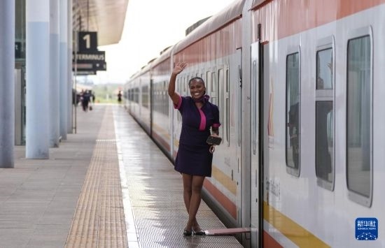 5月31日，在蒙內(nèi)鐵路內(nèi)羅畢站，一名乘務(wù)員在即將開往蒙巴薩的E2次列車旁等候乘客。新華社記者 李亞輝 攝