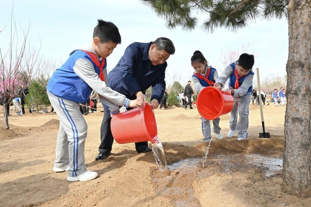 2025年4月3日，習近平總書記等來到北京市豐臺區(qū)永定河畔參加首都義務植樹活動。這是習近平總書記同少先隊員一起給剛栽下的樹苗澆水。新華社記者 謝環(huán)馳 攝